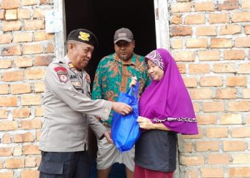 Kasi Humas Polres Muarojambi AKP Armadi saat menyerahkan paket Sembako kepada salah satu warga penerima. [Dok Humas Polres Muarojambi]