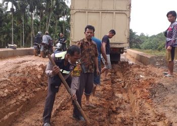 Personel polisi membantu warga yang sedang memperbaiki jalan rusak di Desa Lambur II. [Dok Humas Polda Jambi]