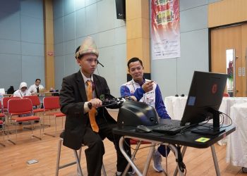 Seorang peserta AHM Best Student tengah mengikuti sesi simulasi presentasi inovasi di hadapan tim pelatih. Didampingi oleh instruktur, peserta mengenakan pakaian adat khas sambil memanfaatkan teknologi digital dalam mendemonstrasikan idenya. Rabu (28/05/2025). (Dok. Sinsnen)