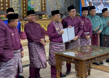 Kepala BPJS Ketenagakerjaan Cabang Jambi, Hendra Elvian (tengah), bersama Wali Kota Jambi, Dr. H. Maulana, MKM, menunjukkan dokumen nota kesepahaman usai penandatanganan MoU perlindungan ketenagakerjaan bagi pekerja non-ASN dan sektor informal di Rapat Paripurna HUT Kota Jambi, Rabu (28/5/2025). (Dok. Yola)