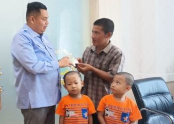 Ketua DPRD Kota Jambi, Kemas Faried Alfarelly, menyerahkan secara simbolis kartu BPJS Ketenagakerjaan kepada ayah Raffi Akbar, siswa penyintas penyakit langka Steven Johnson, didampingi anak-anaknya, Rabu (18/6/2025) di Kantor DPRD Kota Jambi. (Dk. Stepanus)