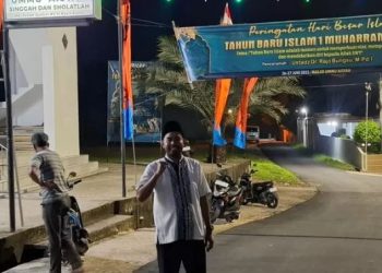 Seorang warga RT 11 Kelurahan Pasir Putih berpose di depan gerbang Masjid Ummu 'Aisyah, lokasi peringatan Tahun Baru Islam 1 Muharram 1447 H yang diisi pawai obor dan tausiyah, Kamis (26/6/2025) malam. (Dok. Yola)