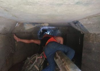 Petugas UPTD PUPR membersihkan saluran drainase sempit di bawah jalan utama Kota Jambi, Selasa (4/6/2025). (Dok. Nahar)