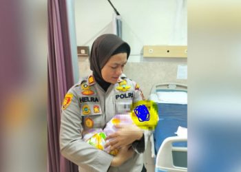 Kapolsek Jambi Selatan AKP Helrawati menggendong bayi perempuan yang ditemukan di bawah jendela Panti Sosial Harapan Mulya, Kamis (5/6/2025). (Dok Stepanus)