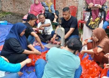 Warga dan relawan tim Misoan Diva dan Catering Diva bersama-sama mengemas daging kurban dalam kegiatan distribusi 1.000 paket daging di Kelurahan Kebun Handil, Kecamatan Jelutung, Kota Jambi, Jumat (6/6/2025). (Foto: Yola)