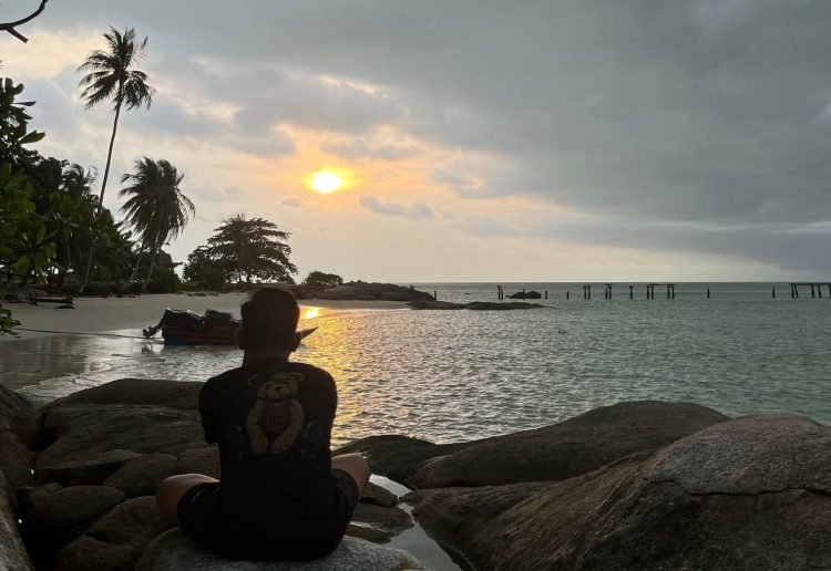 Surya duduk tenang di atas batu pesisir Pulau Berhala, menikmati senja yang perlahan tenggelam, Sabtu (31/05/2025).(Foto: Surya Paramata)