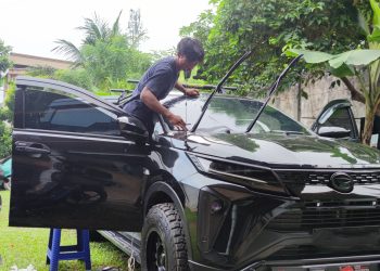 Fajar saat memasang kaca film pada mobil pelanggan di halaman rumah, Jumat (2/5). (Dok. Stepanus)