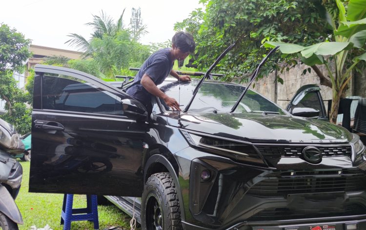 Fajar saat memasang kaca film pada mobil pelanggan di halaman rumah, Jumat (2/5). (Dok. Stepanus)