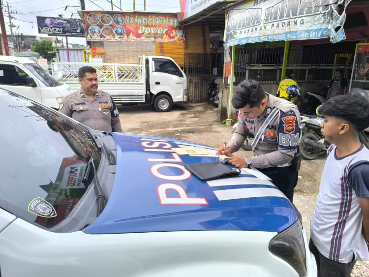 Petugas Satlantas Polresta Jambi menulis surat tilang kepada salah satu pengendara yang melanggar aturan dalam operasi penegakan hukum lalu lintas, Senin (14/7/2025). (Dok. Nahar)