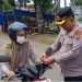 Kapolres Tanjab Timur AKBP Maulia Kuswicaksono membagikan bendera merah putih kepada seorang pengendara di simpang empat Sate, Muara Sabak Barat, Senin (5/8/2025). (Daus)