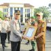 Kapolda Jambi Irjen Pol Krisno H. Siregar menyerahkan piagam penghargaan pada Rapulis, S.E., selaku Lurah Rawasari usai apel pagi di Lapangan Hitam Mapolda Jambi pada Senin (4/8/2025). (Nahar)