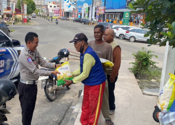 Anggota Satlantas Polda Jambi membagikan bantuan beras kepada warga dalam kegiatan bakti sosial memperingati Hari Lalu Lintas Bhayangkara ke-70, Selasa (16/9/2026). (Dok. Nahar)