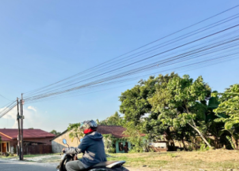 Seorang warga melintas di Kota Jambi pada siang terik, Selasa (23/9/2026). (Dok. Stepanus)