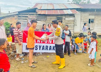 Kapolsek Berbak Ipda Hans Simangunsong menyerahkan bantuan paket sembako kepada warga terdampak banjir di Kelurahan Simpang, Kabupaten Tanjung Jabung Timur, Jumat (12/9/2025). (dok. Humas)
