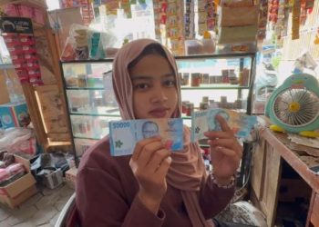 Seorang pedagang di Kota Jambi memperlihatkan uang palsu pecahan Rp50.000 dan Rp100.000 yang diterimanya saat bertransaksi di toko kelontong, Kamis (18/9/2025). (Dok. Nahar)