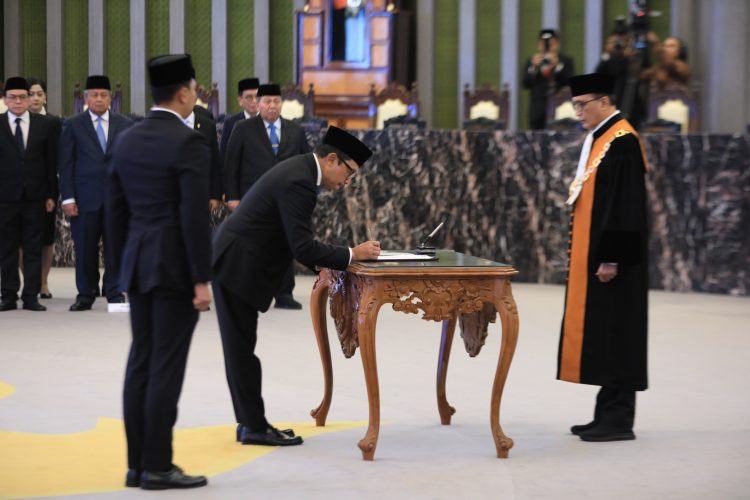 Deputi Gubernur Bank Indonesia Juda Agung menandatangani berita acara pelantikan sebagai Anggota Dewan Komisioner OJK Ex-officio BI, disaksikan Ketua Mahkamah Agung RI Sunarto di Gedung MA Jakarta, Selasa (23/9/2025). (Dopk. Humas OJK Jambi)