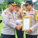 Kapolres Tanjung Jabung Timur AKBP M. Kuswicaksono, S.I.K., M.H. menyerahkan piagam penghargaan kepada Kapolsek Berbak IPDA Hansmadi Simangunsong pada upacara di lapangan Polres Tanjab Timur, Senin (6/10/2025). (Dok. Humas)
