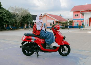 Seorang siswi SMA di Jambi berpose bersama motor Yamaha Fazzio berwarna merah di halaman sekolah. (Dok. Stepanus)
