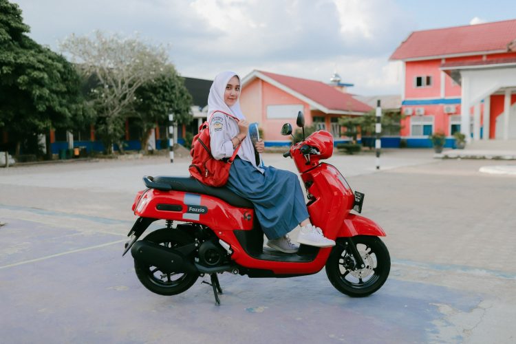 Seorang siswi SMA di Jambi berpose bersama motor Yamaha Fazzio berwarna merah di halaman sekolah. (Dok. Stepanus)