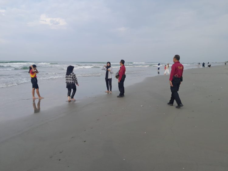 Anggota Ditpamobvit Polda Bengkulu berdialog dengan wisatawan saat melaksanakan patroli di Pantai Pasir Putih, Bengkulu, Minggu (12/10/2025). (Dok. Yola)