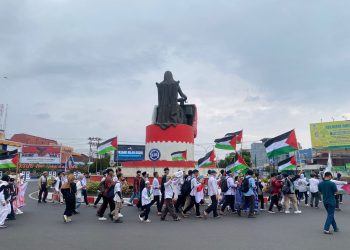Sejumlah peserta aksi dari PW KAMMI Bengkulu mengibarkan bendera Palestina saat menggelar aksi damai di kawasan pusat Kota Bengkulu, Senin (13/10/2025). (Yola)
