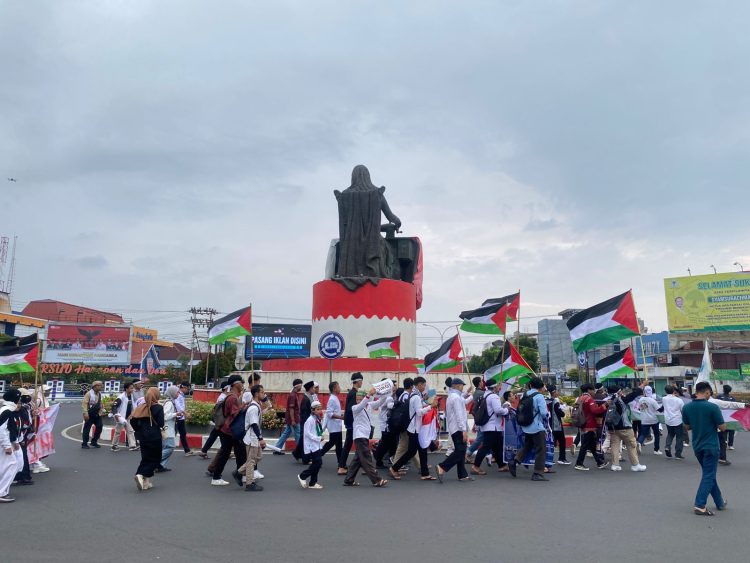Sejumlah peserta aksi dari PW KAMMI Bengkulu mengibarkan bendera Palestina saat menggelar aksi damai di kawasan pusat Kota Bengkulu, Senin (13/10/2025). (Yola)