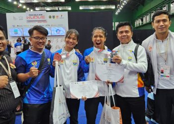 Manajer tim wushu Jambi Rio Setiadi (kiri) bersama atlet dan pelatih berpose menunjukkan medali yang diraih usai pertandingan cabang wushu pada PON Bela Diri 2025 di GOR Djarum Kaliputu, Kudus, Jawa Tengah, Minggu (26/10/2025). (Dok. Humas KONI)