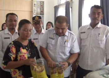 Kepala Dinas Ketahanan Pangan Kabupaten Tanjung Jabung Timur, Nasrul Efendi, bersama warga memeriksa paket bantuan beras dan minyak goreng dari Bapanas pada penyaluran bantuan pangan alokasi Oktober–November 2025. (Dok. Stepanus)