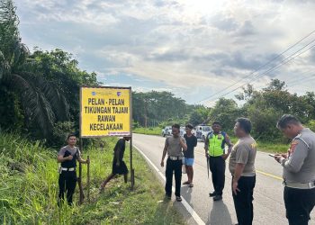 Petugas Jasa Raharja bersama anggota Kepolisian memasang spanduk imbauan keselamatan lalu lintas di salah satu titik rawan kecelakaan di Provinsi Jambi sebagai upaya pencegahan dan peningkatan kewaspadaan pengendara. (Dok,. Nahar)