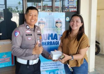 Personel Subdit Regident Ditlantas Polda Jambi membagikan makanan gratis kepada masyarakat dalam kegiatan Jumat Berkah di area Samsat Kota Jambi, Jumat (24/4/2026). (Dok, Nahar)