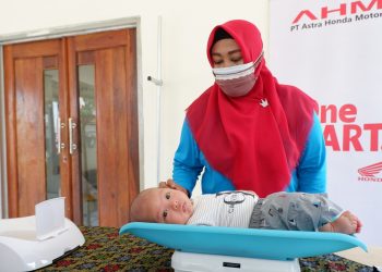 Seorang kader kesehatan melakukan penimbangan bayi di Posyandu Desa Sukamukti, Bekasi, Jawa Barat, dalam program pelatihan dan penguatan layanan kesehatan yang didukung PT Astra Honda Motor (AHM). (Dok. Sinsen)