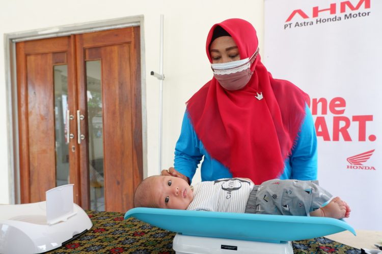Seorang kader kesehatan melakukan penimbangan bayi di Posyandu Desa Sukamukti, Bekasi, Jawa Barat, dalam program pelatihan dan penguatan layanan kesehatan yang didukung PT Astra Honda Motor (AHM). (Dok. Sinsen)