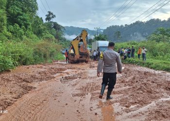 Petugas kepolisian bersama alat berat melakukan penanganan material longsor yang menutupi Jalan Lintas Kerinci–Bangko di Desa Muara Hemat, Kecamatan Batang Merangin, Kabupaten Kerinci, Jumat (8/5/2026). (Dok. Humas)